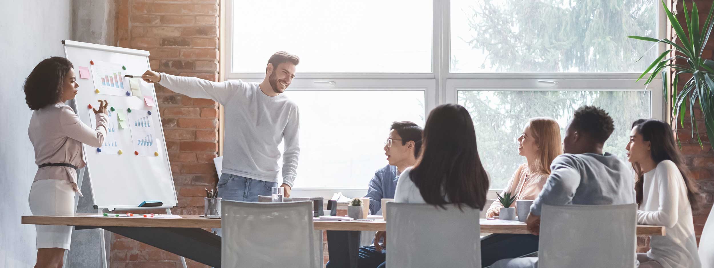 A team of office workers listening to a presentation by two of their coworkers.