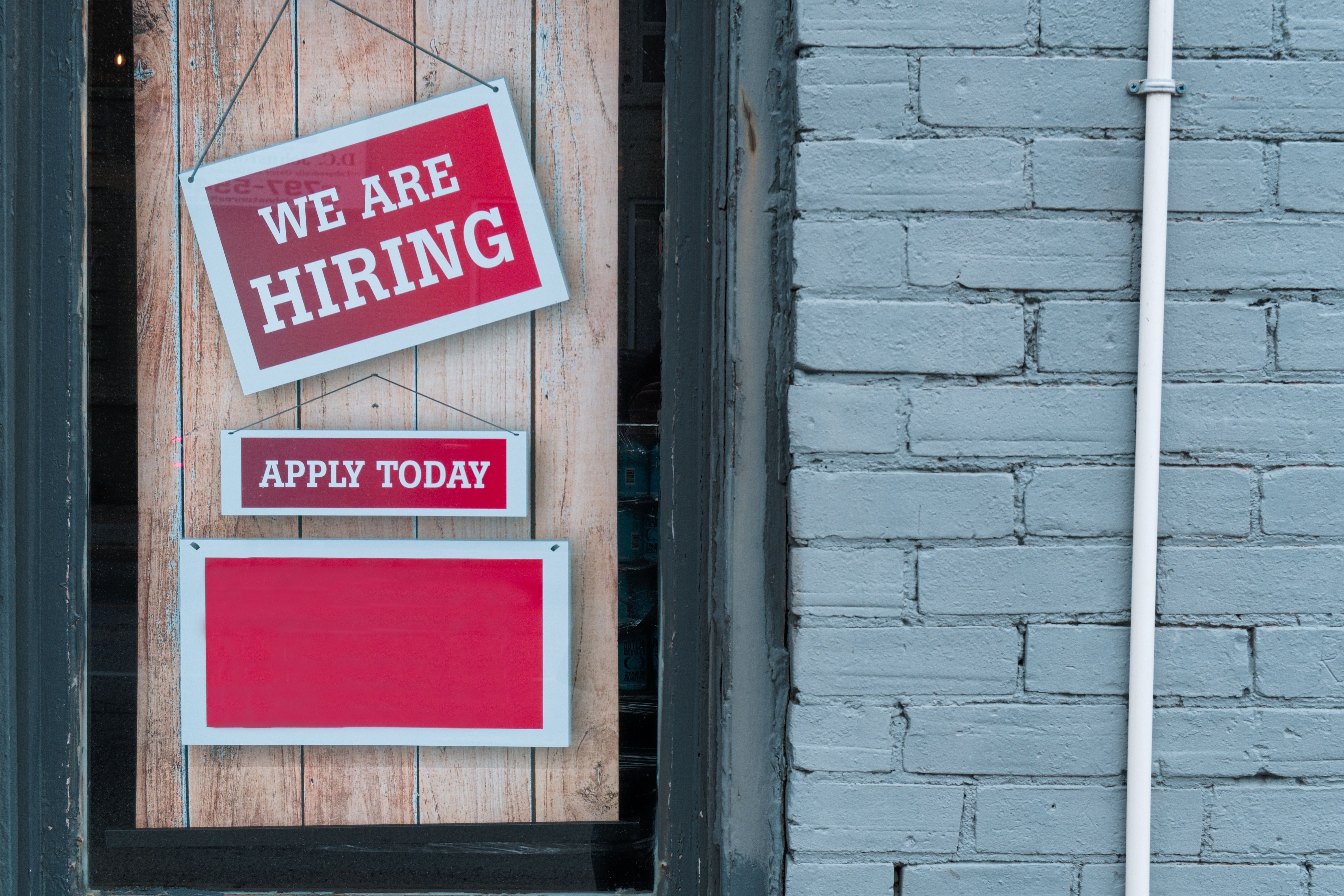 An image of a "We are hiring" sign in a business window